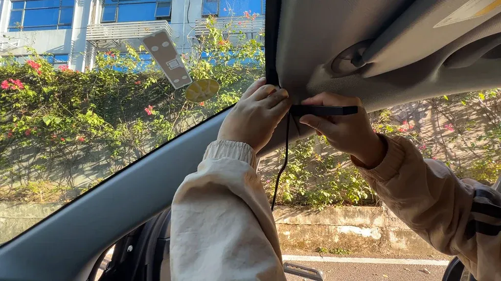 Dash cam power cable being tucked into the headlining and A-pillar trim so nothing shows on the glass