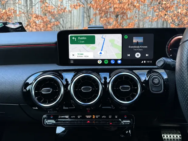 Android Auto on a Mercedes factory screen with Google Maps navigation to Dublin and Spotify playing side by side